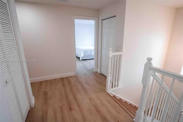 a view of a hallway with wooden floor and staircase