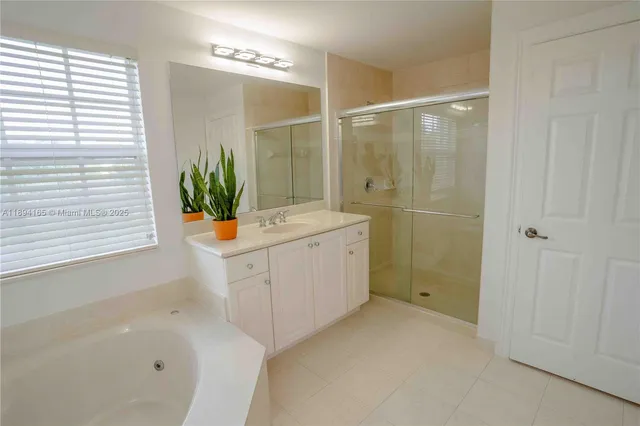 a bathroom with a sink a granite tub shower and a mirror
