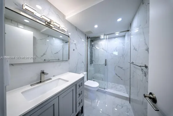 a bathroom with a sink a toilet a mirror and shower