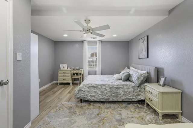 a spacious bedroom with a bed a dresser and lots of books