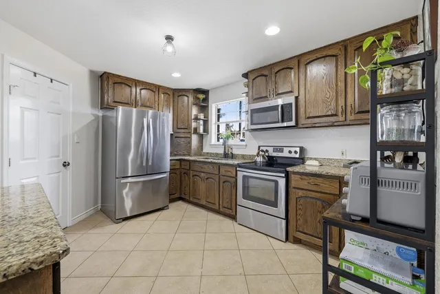 a kitchen with stainless steel appliances granite countertop a refrigerator stove top oven and sink