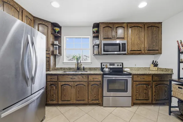 a kitchen with stainless steel appliances granite countertop a refrigerator stove and sink