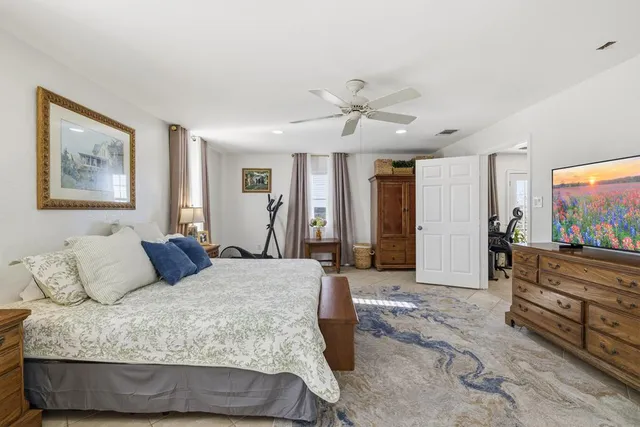 a bedroom with a large bed a flat tv screen and a dresser