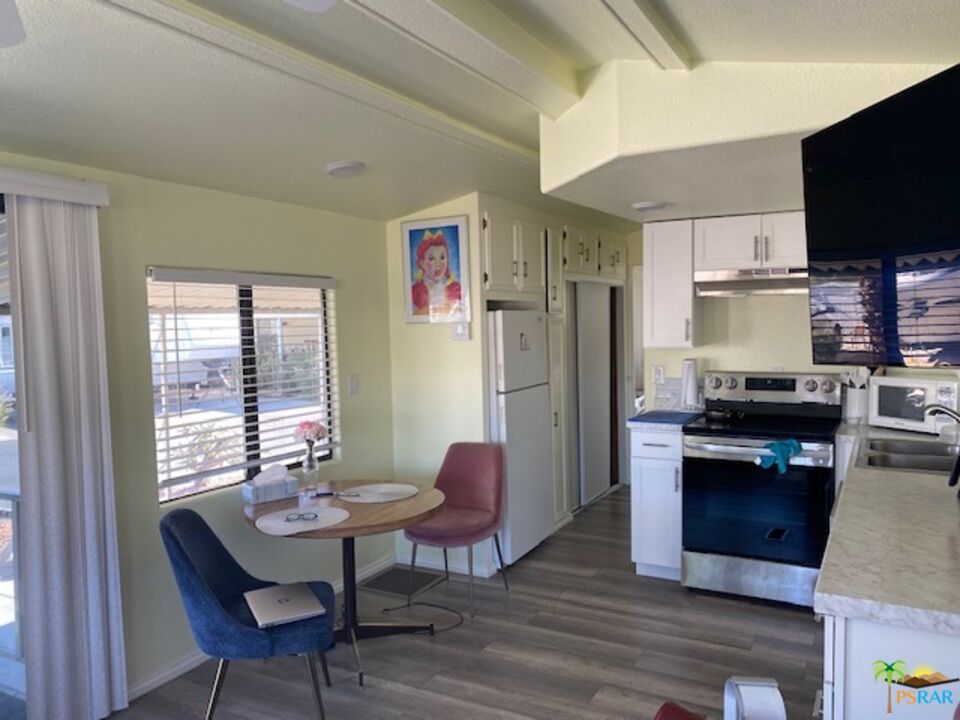 69801 Ramon Road, Unit 161 Cathedral City, CA 92234 - Photo 5 of 9 a kitchen with stainless steel appliances granite countertop a refrigerator a stove a sink dishwasher and a microwave oven with wooden floor
