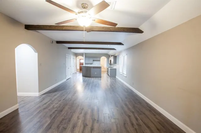 a view of an empty room with wooden floor fireplace and a window