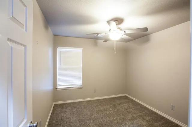 an empty room with a chandelier fan and closet area