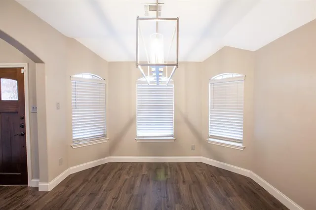 an empty room with wooden floor and window