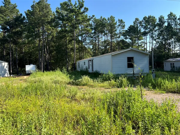 a house is sitting in middle of the green field