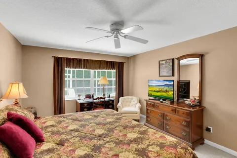 a bedroom with a bed flat screen tv and windows