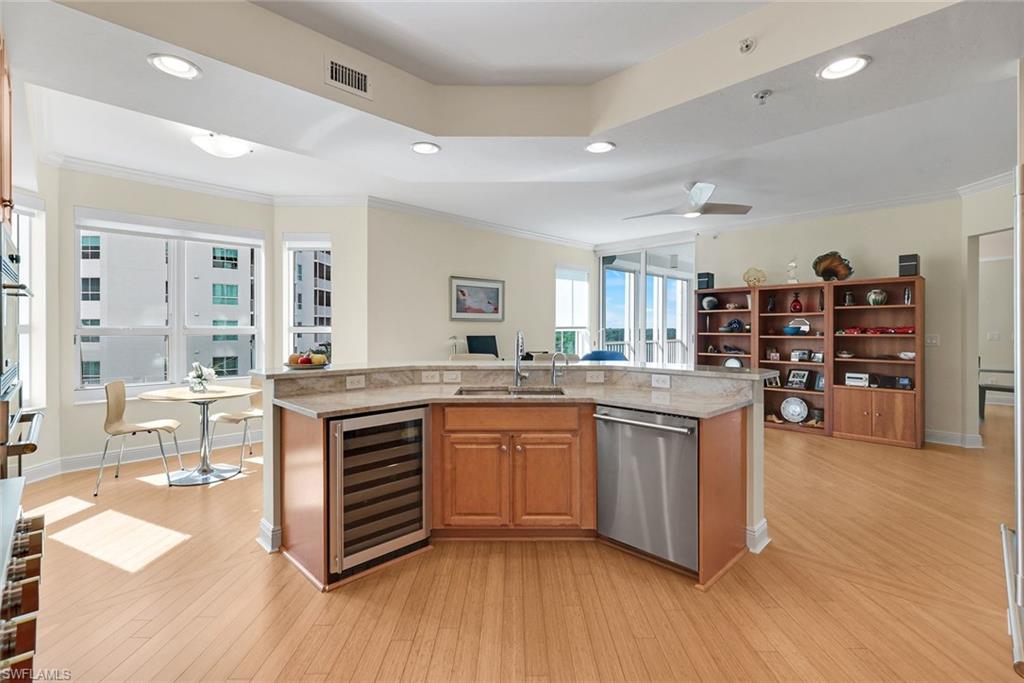 285 Grande Way, Unit 401 Naples, FL 34110 - Photo 15 of 50 a open kitchen with granite countertop a stove top oven a sink dishwasher and white cabinets with wooden floor