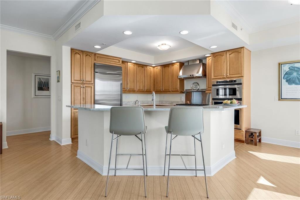 285 Grande Way, Unit 401 Naples, FL 34110 - Photo 17 of 50 a kitchen with stainless steel appliances kitchen island granite countertop a stove a refrigerator a sink a dining table and chairs with wooden floor