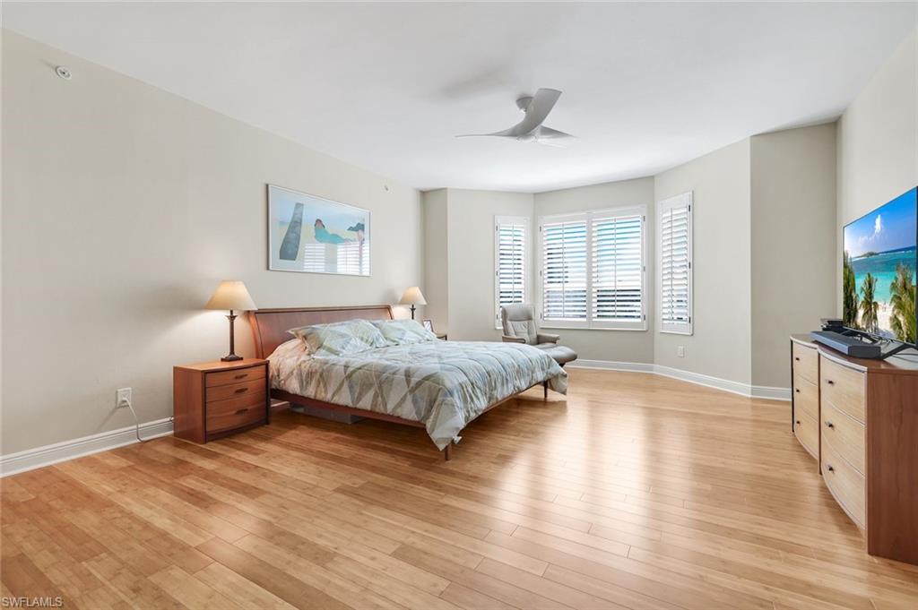 285 Grande Way, Unit 401 Naples, FL 34110 - Photo 22 of 50 a spacious bedroom with a large bed and a chandelier