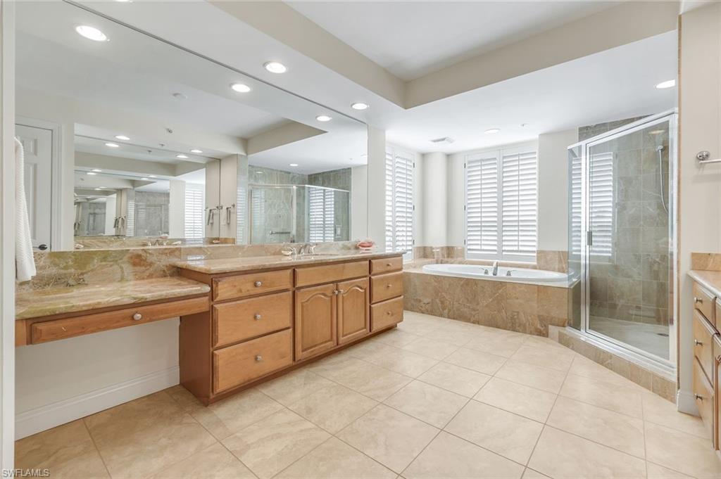 285 Grande Way, Unit 401 Naples, FL 34110 - Photo 25 of 50 a large bathroom with a large mirror vanity and shower