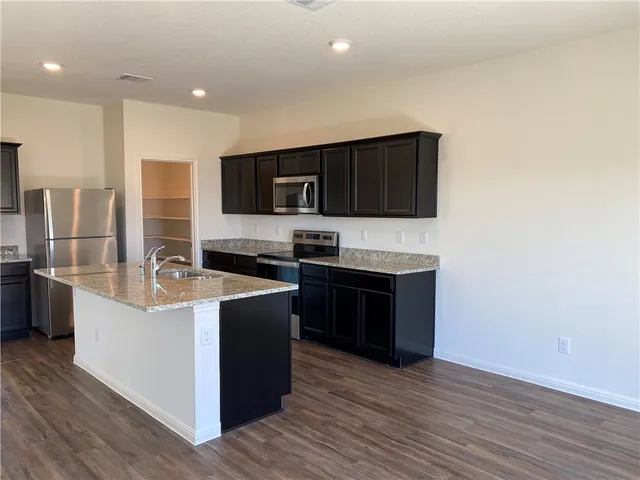 a kitchen with a sink granite counter tops and a window