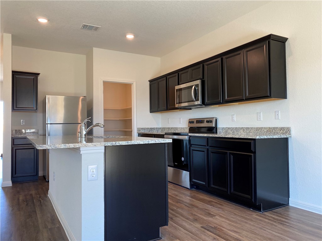 12901 Robert Lafollette Road Manor, TX 78653 - Photo 4 of 29 a kitchen with stainless steel appliances granite countertop wooden cabinets a stove top oven a sink and dishwasher