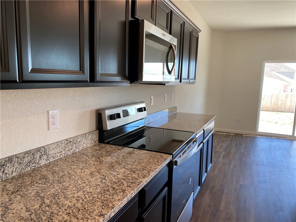 12901 Robert Lafollette Road Manor, TX 78653 - Photo 5 of 29 a kitchen with stainless steel appliances granite countertop a sink a stove and a wooden floor