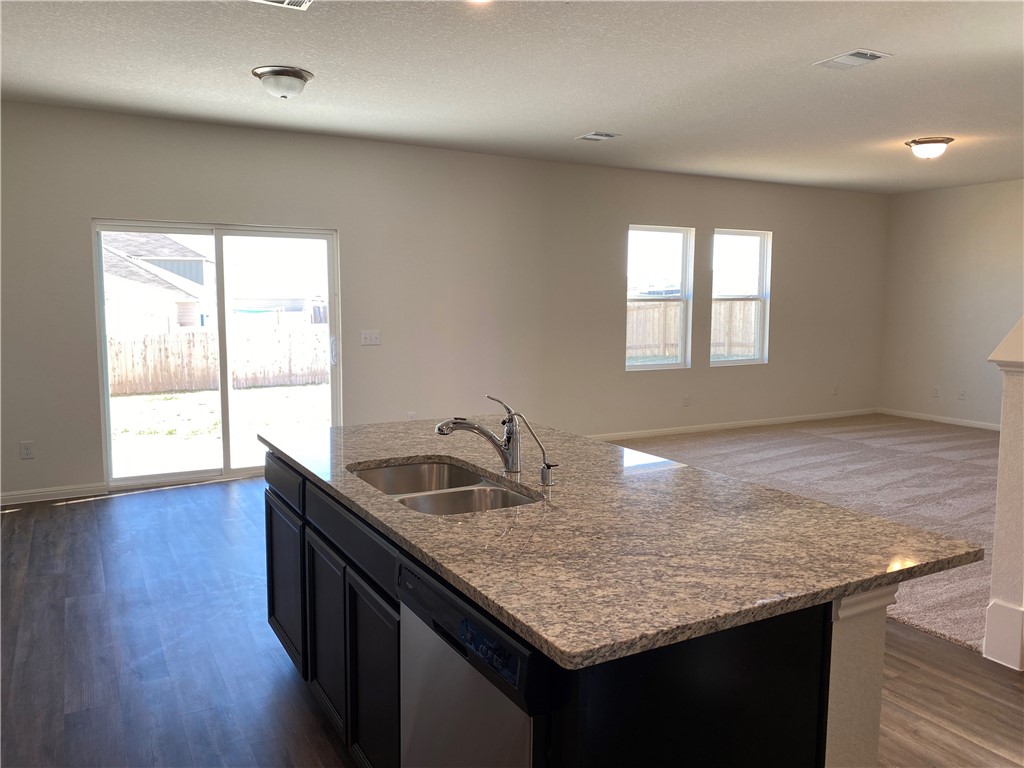 12901 Robert Lafollette Road Manor, TX 78653 - Photo 6 of 29 a kitchen with granite countertop kitchen island stainless steel appliances a sink stove and wooden floor