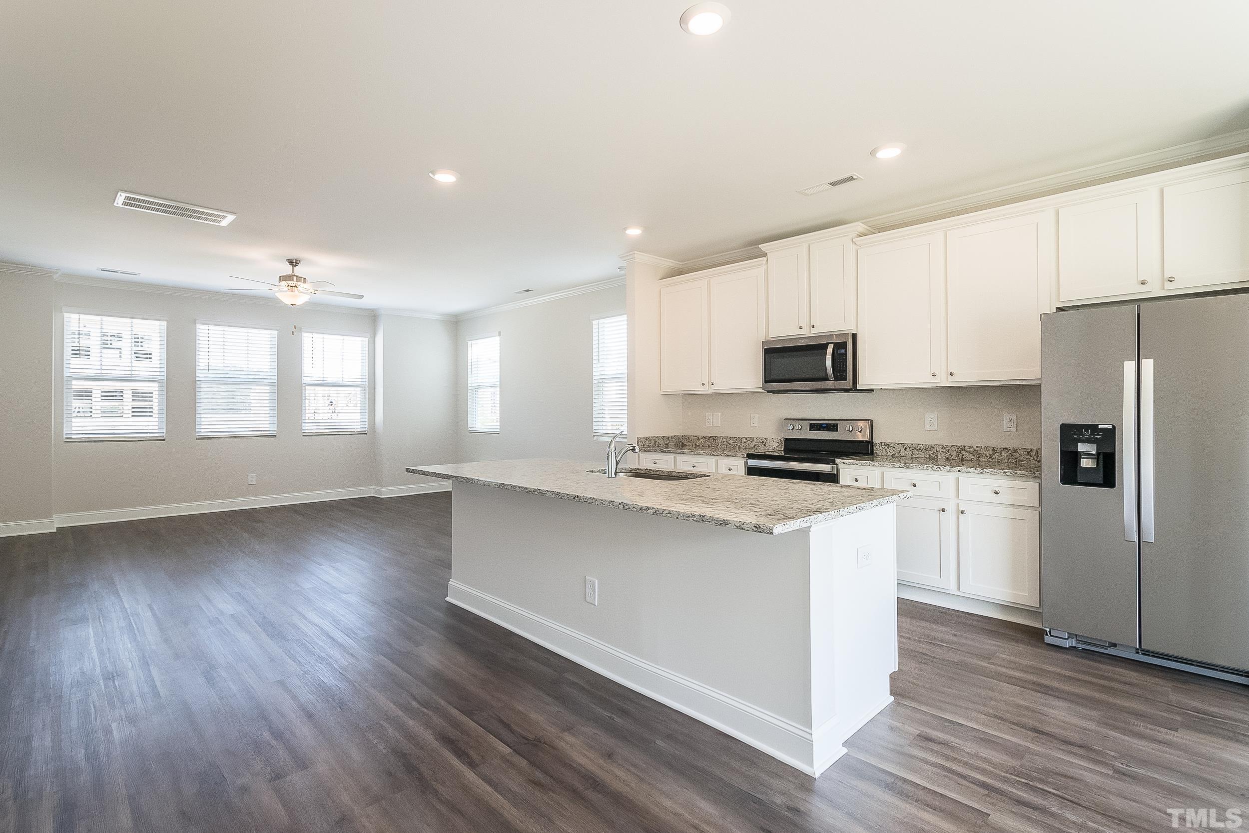 6945 Point Bar Place Raleigh, NC 27616 - Photo 3 of 10 a kitchen with granite countertop a refrigerator a sink dishwasher a stove and white cabinets with wooden floor