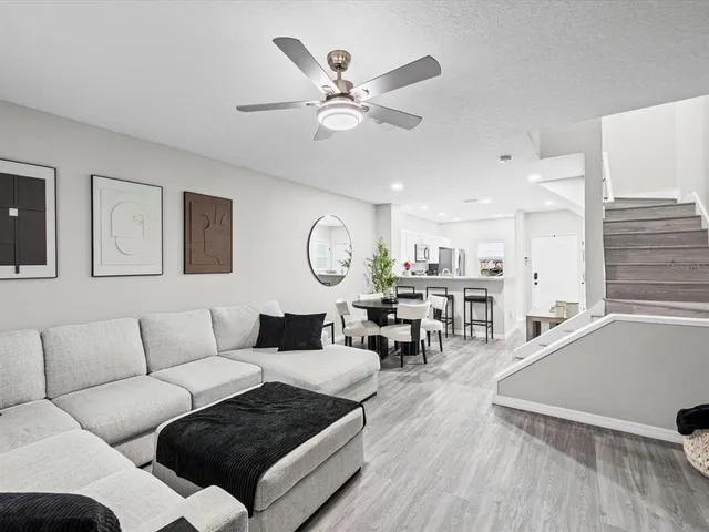 a living room with furniture kitchen view and a large window