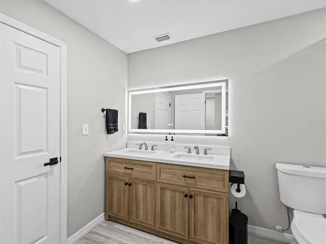 a bathroom with a double vanity sink toilet and mirror