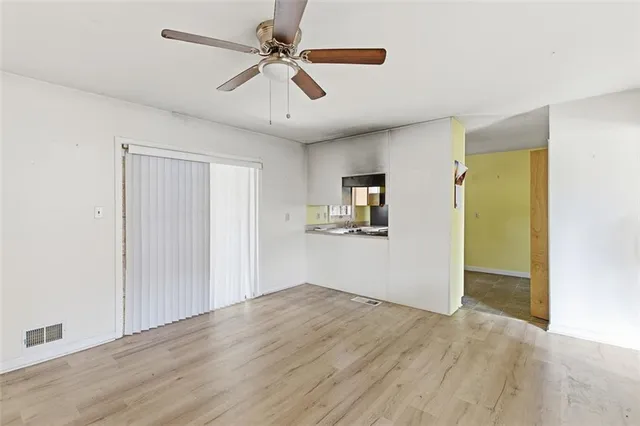 a view of empty room with wooden floor and ceiling fan