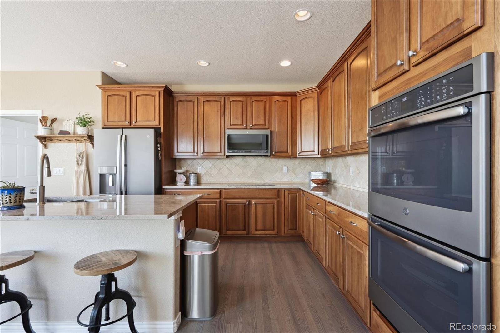 724 Imboden Road Watkins, CO 80137 - Photo 12 of 50 a kitchen with stainless steel appliances granite countertop a refrigerator a sink dishwasher a stove and white countertops with wooden floor