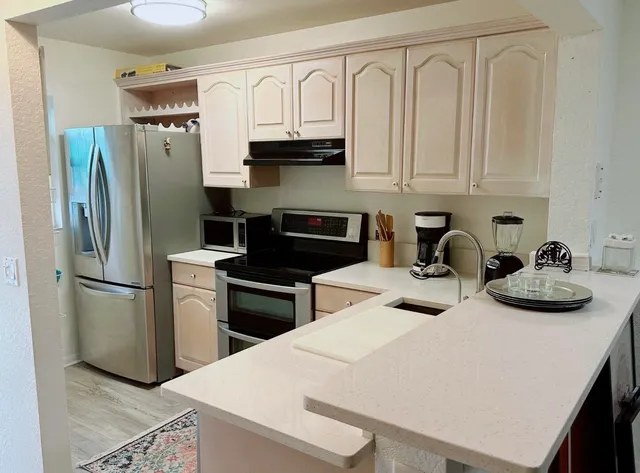 a kitchen with stainless steel appliances a refrigerator a sink a stove and white cabinets