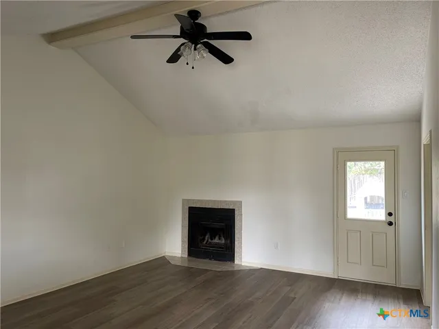 an empty room with wooden floor chandelier fan and windows