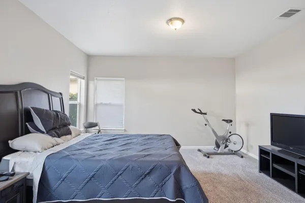 a bedroom with a bed and a flat tv screen on the dresser