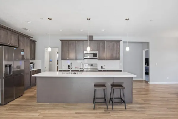 a kitchen with stainless steel appliances granite countertop a sink a stove a refrigerator island and chairs