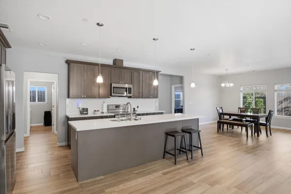 a large white dining hall with stainless steel appliances granite countertop a dining table chairs and granite counter tops