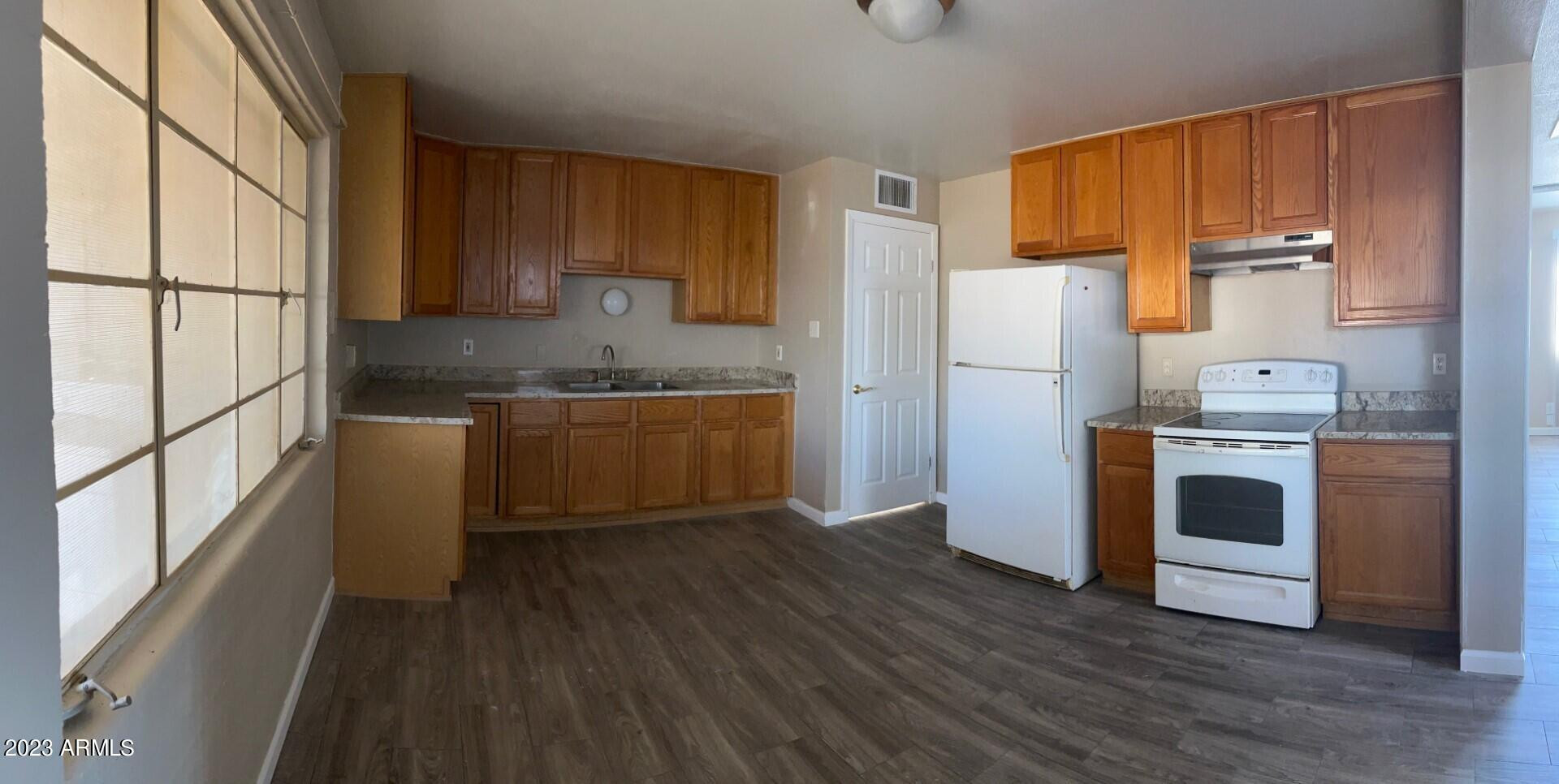 a kitchen with stainless steel appliances a stove a refrigerator and a sink with wooden floor