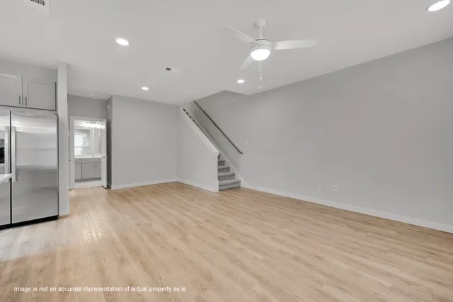 an empty room with wooden floor and staircase