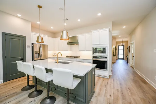 a kitchen with a refrigerator a sink dishwasher a oven and a dining table with wooden floor