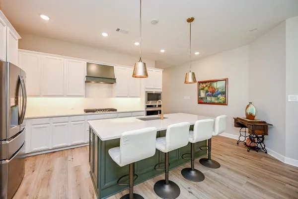 a kitchen with stainless steel appliances a dining table chairs refrigerator and sink