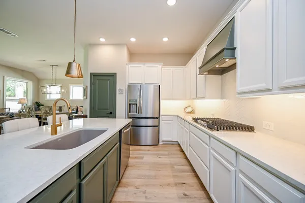 a large kitchen with a large counter top a sink a refrigerator and cabinets