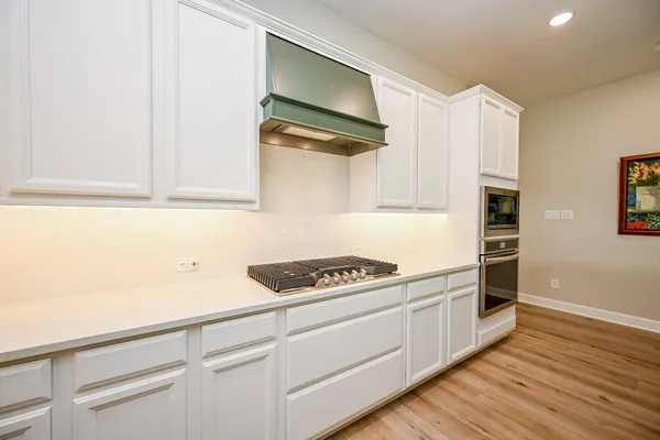 a kitchen with cabinets stainless steel appliances and wooden floor