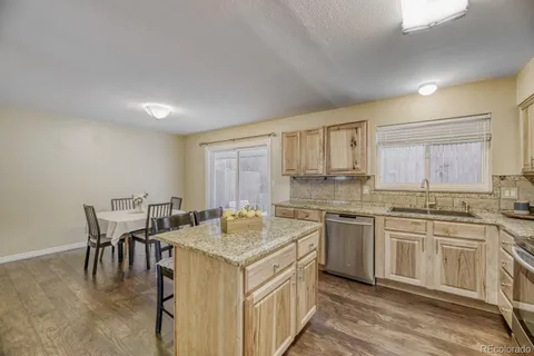 a kitchen with a sink stove and white cabinets with wooden floor