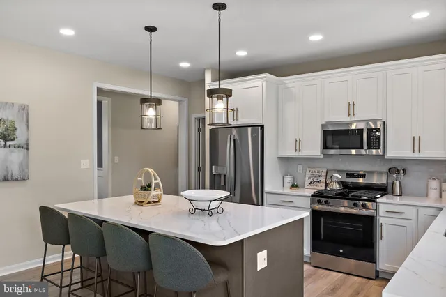 a kitchen with stainless steel appliances granite countertop a sink a stove a refrigerator and island with wooden floor