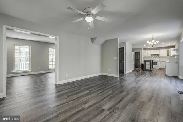 an empty room with wooden floor fireplace and windows