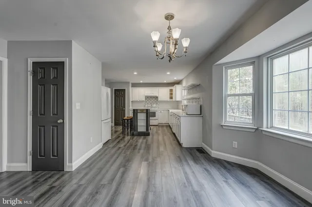 a view of an empty room with wooden floor fireplace and a window