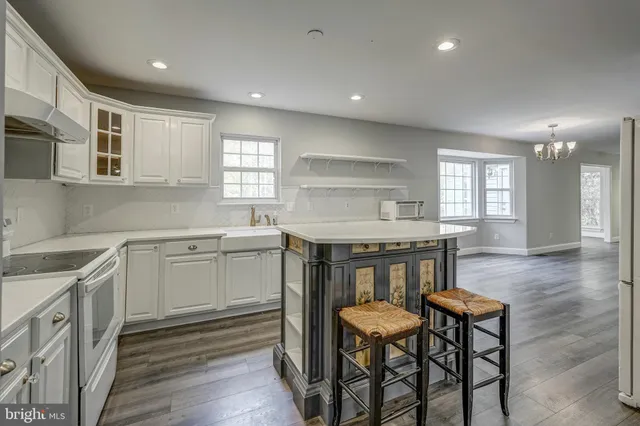 an empty room with wooden floor windows and a chandelier