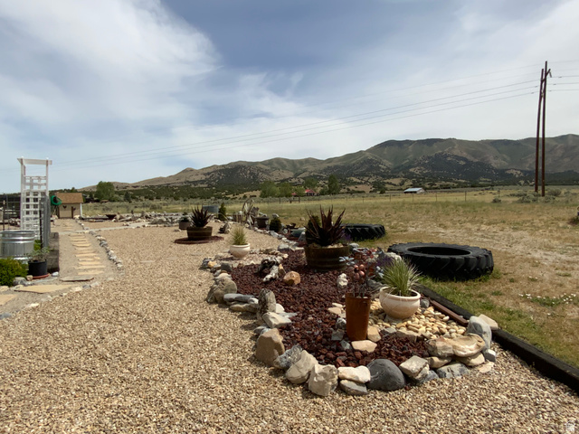1061 Copper Street Stockton, UT 84071 - Photo 36 of 43 Gravel pathways and rock-lined landscaping beds define the outdoor space, featuring a white trellis structure and distant mountain scenery