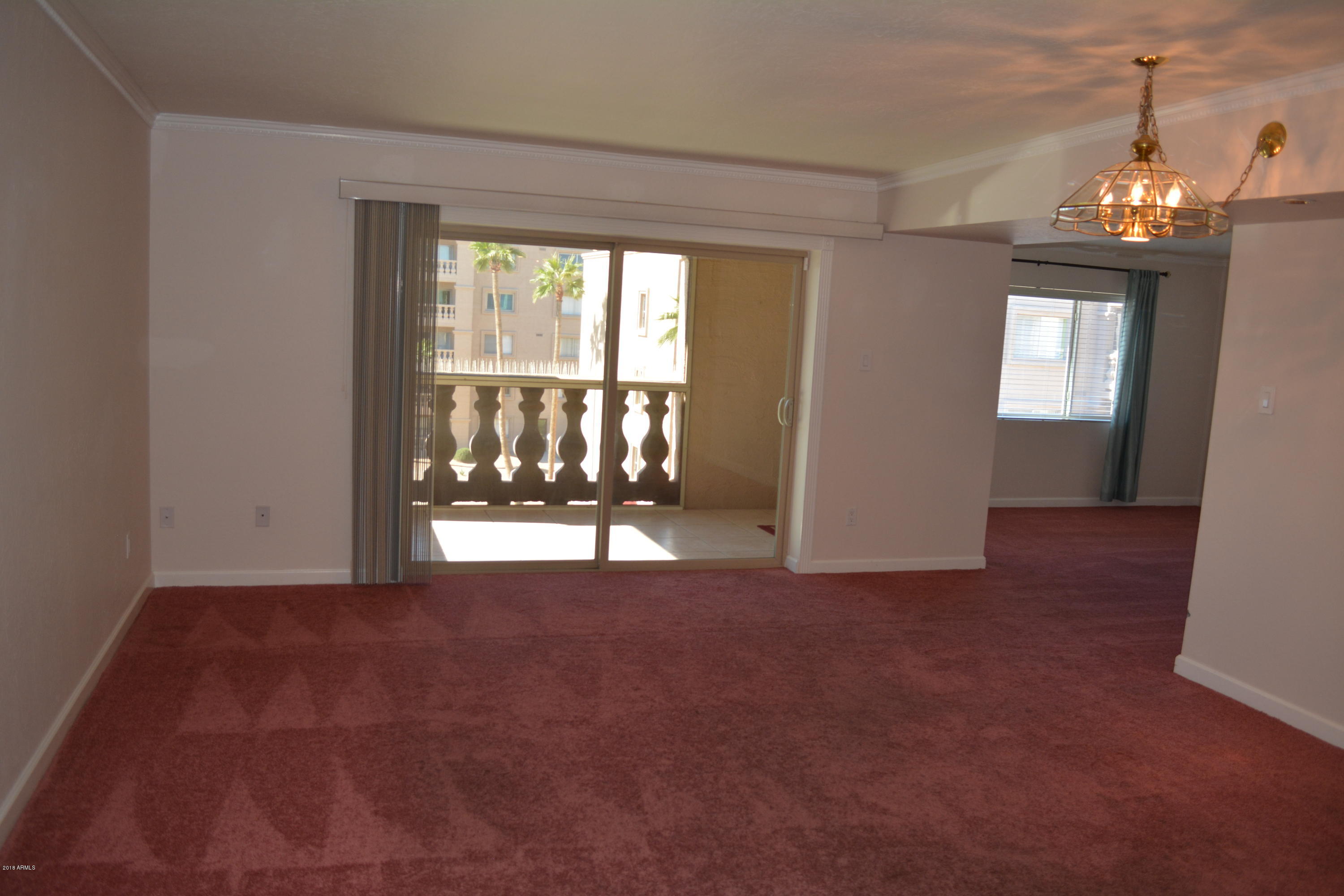 7870 East Camelback Road, Unit 412 Scottsdale, AZ 85251 - Photo 3 of 15 an empty room with chandelier fan and windows