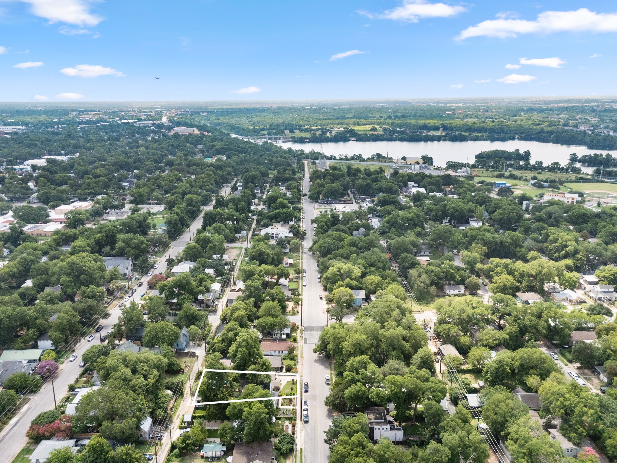 1908 Holly Street Austin, TX 78702 - Photo 15 of 22 An aerial perspective reveals a tree-lined neighborhood alongside a serene body of water under a wide blue sky.