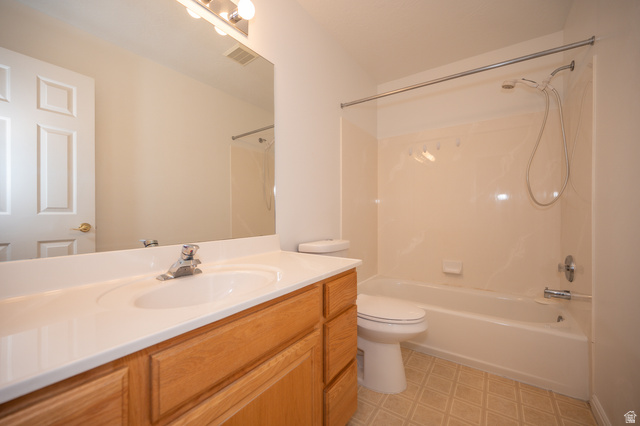 1799 West 1110th Street North Provo, UT 84604 - Photo 19 of 24 Full bathroom featuring a wood-finish vanity with an integrated sink, a large wall-mounted mirror, a three-light vanity fixture, a toilet, and a combined tub and shower unit with a shower curtain rod
