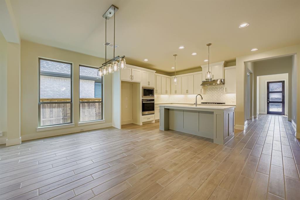 130 Pecan Lane Rhome, TX 76078 - Photo 9 of 28 Kitchen featuring tasteful backsplash, hanging light fixtures, an island with sink, light wood-style floors, and recessed lighting