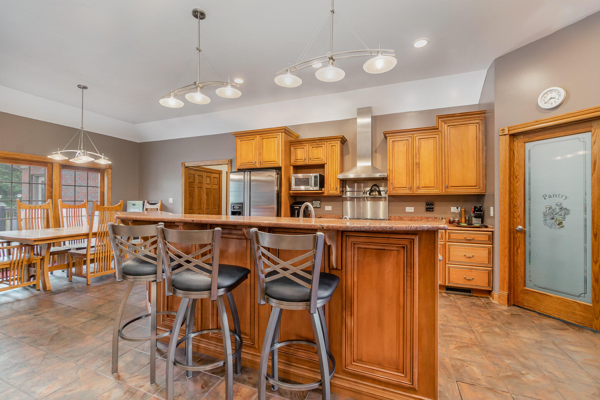 8855 East 93rd Avenue Crown Point, IN 46307 - Photo 5 of 41 a kitchen with stainless steel appliances granite countertop wooden cabinets a dining table and chairs a refrigerator with wooden floor