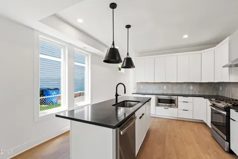 a kitchen with stainless steel appliances granite countertop a sink a stove a refrigerator and island with wooden floor