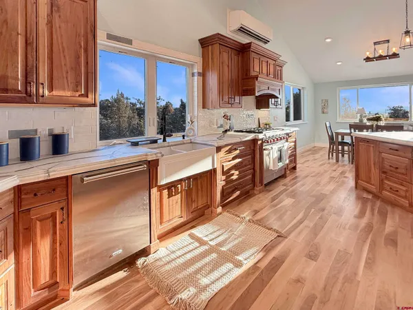 a kitchen with granite countertop wooden floors wooden cabinets and stainless steel appliances